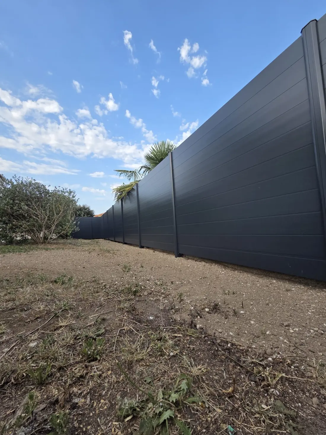 Clôture pleine en aluminium gris anthracite protégeant l'intimité d'un jardin, réalisée par Clôtures et Créations